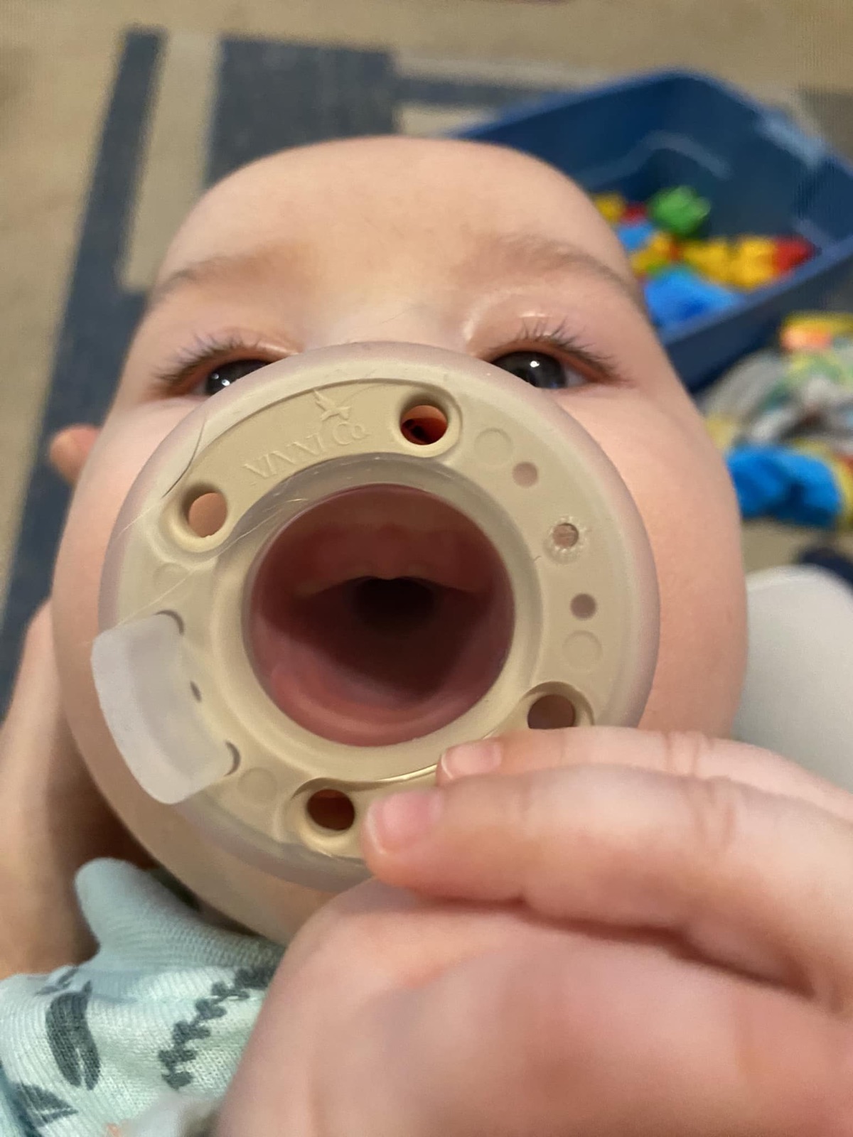 An infant looking through a pacifier