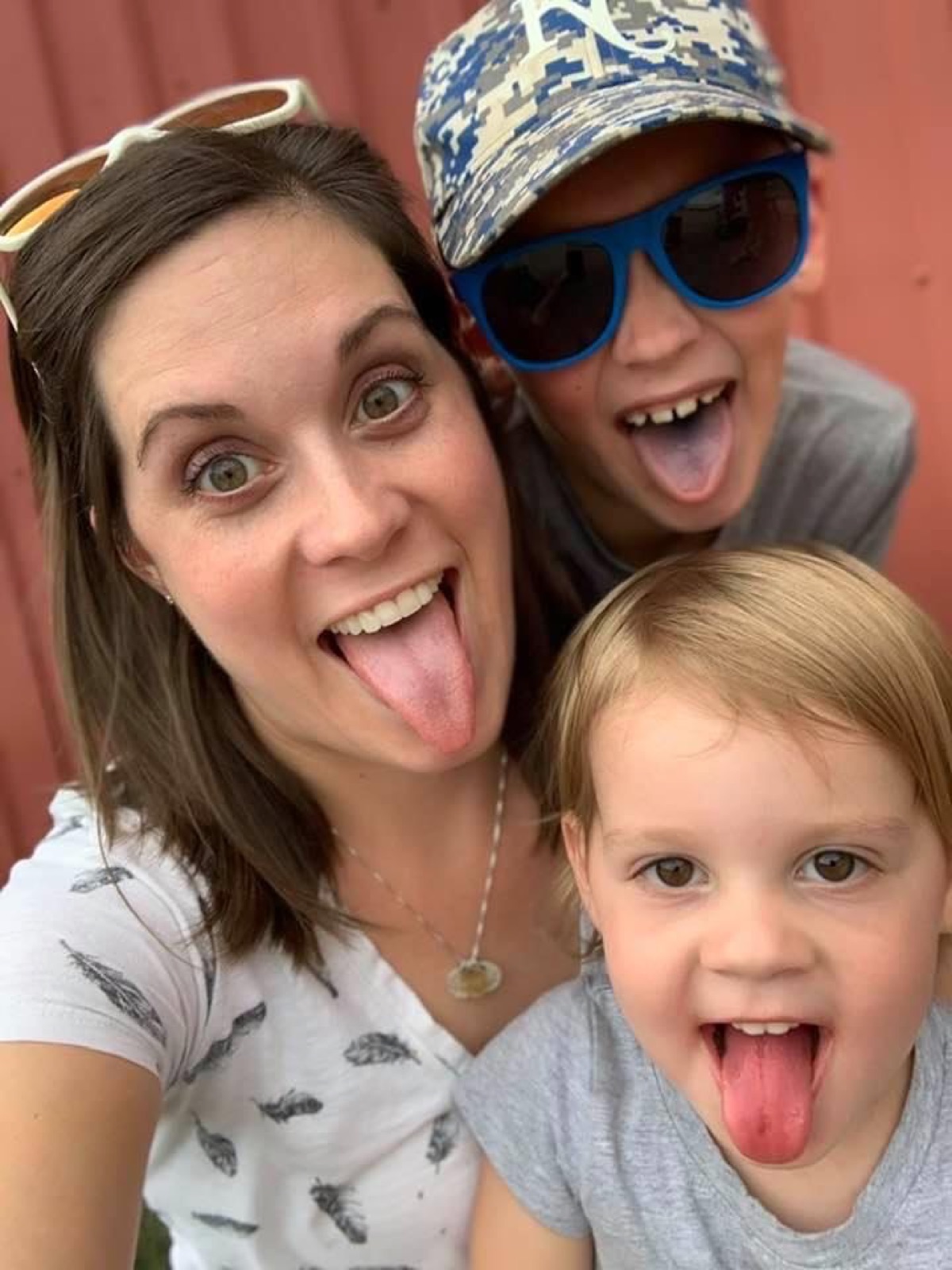 A mom and her two children playfully sticking their tongues out