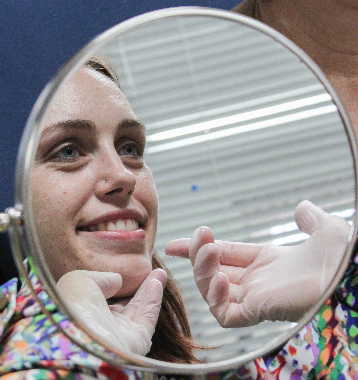 A patient practicing correct tongue placement at a mirror during therapy