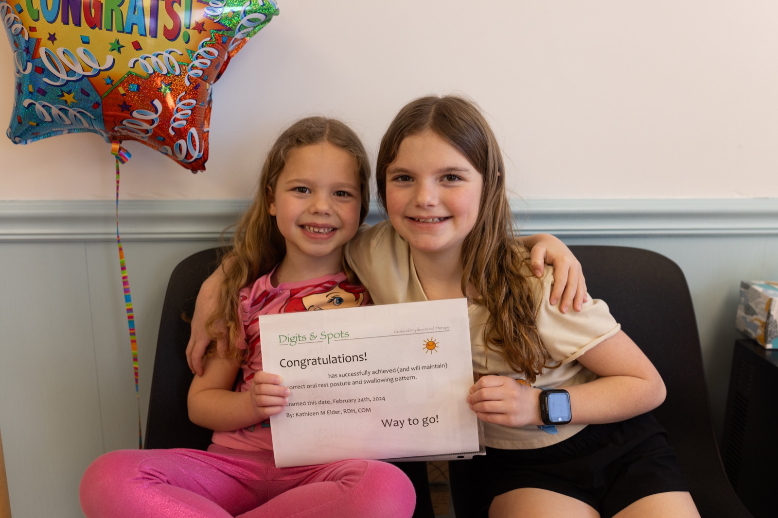 Two girls holding a congratulations certificate for completing therapy